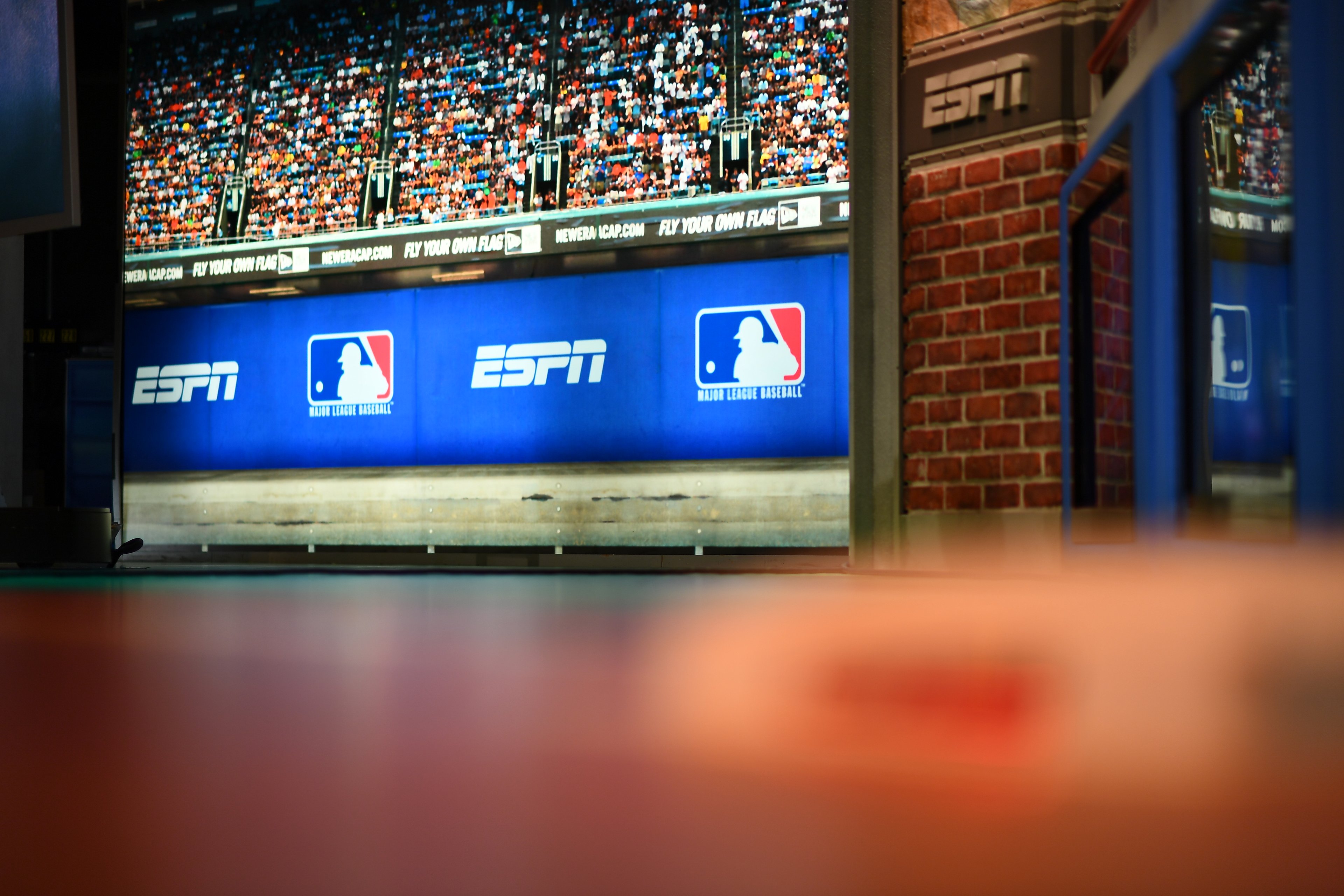 The set in an ESPN studio showing an image of an ESPN ad on a banner at a baseball game.