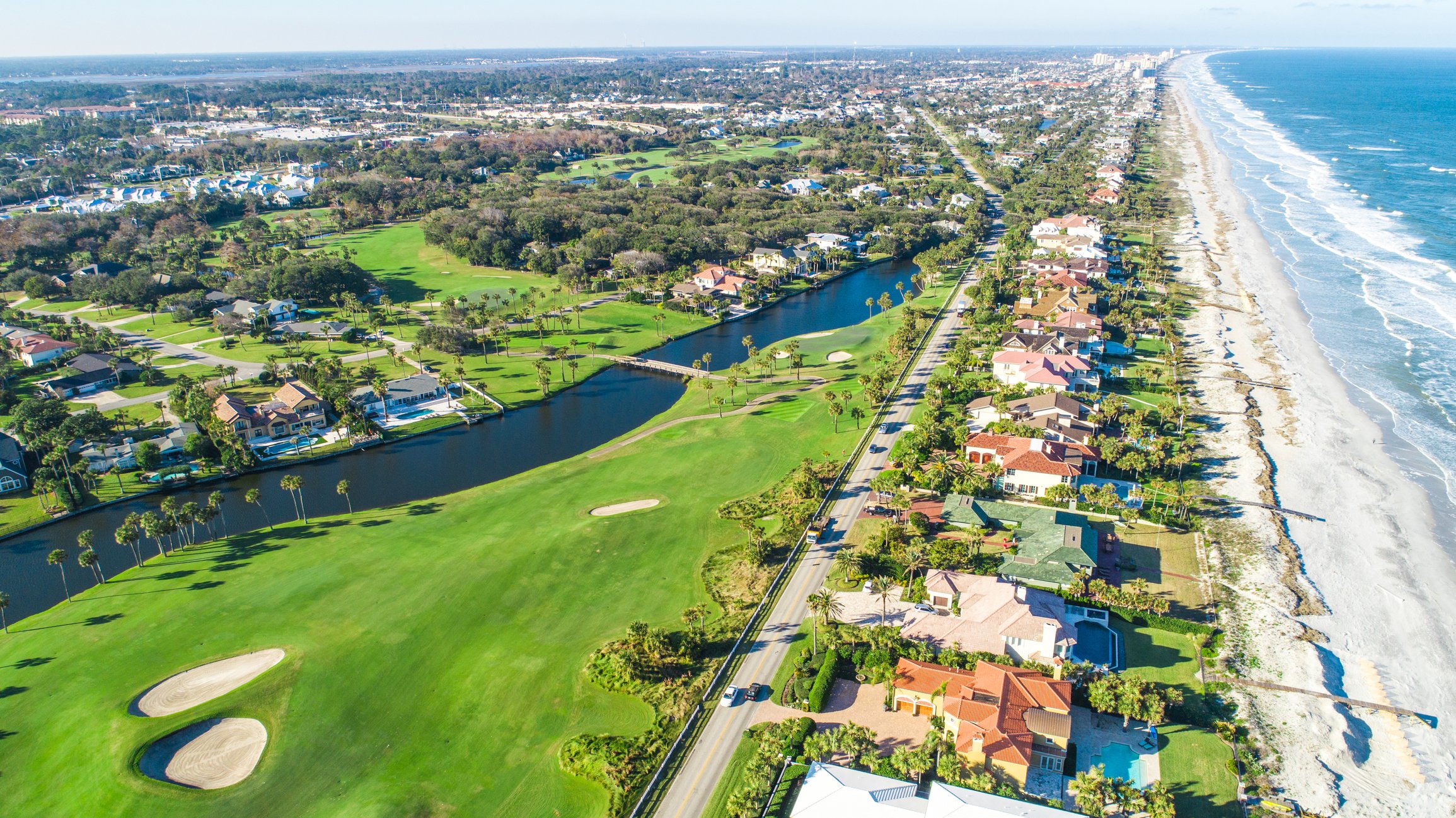 Aerial view of neighborhood between a beach and a golf course