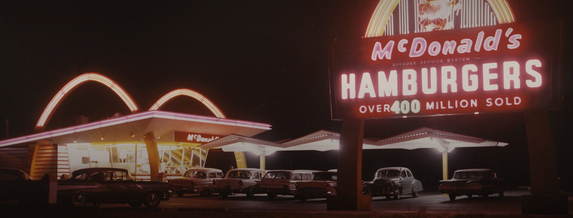 Old-school McDonald's restaurant at night, with a sign declaring more than 400 million burgers sold.