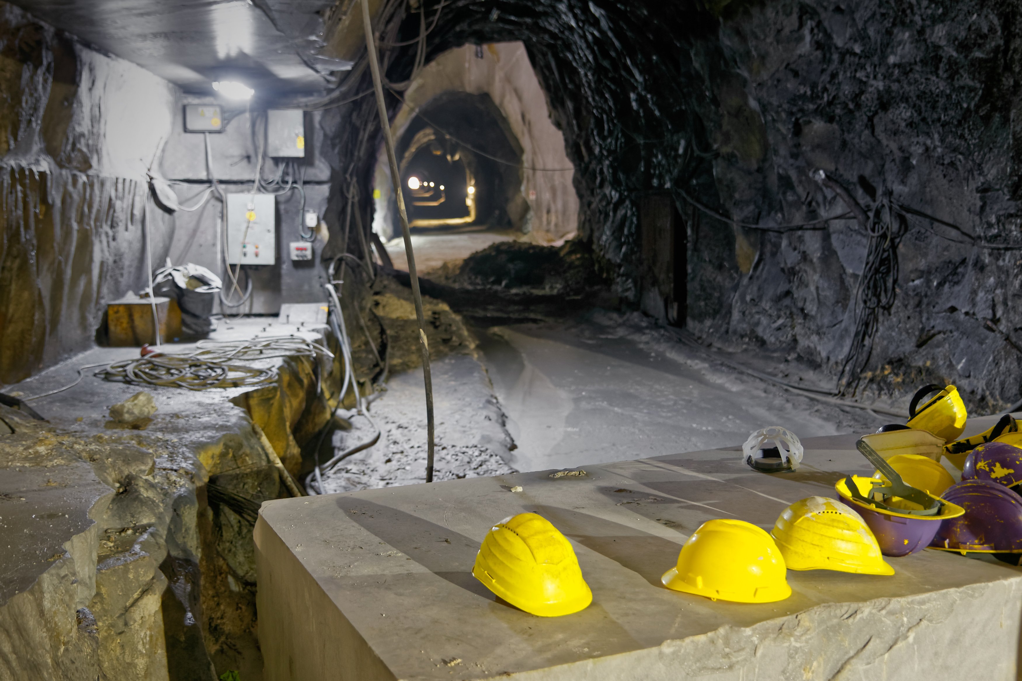An underground mine, with yellow hard hats resting on a surface.