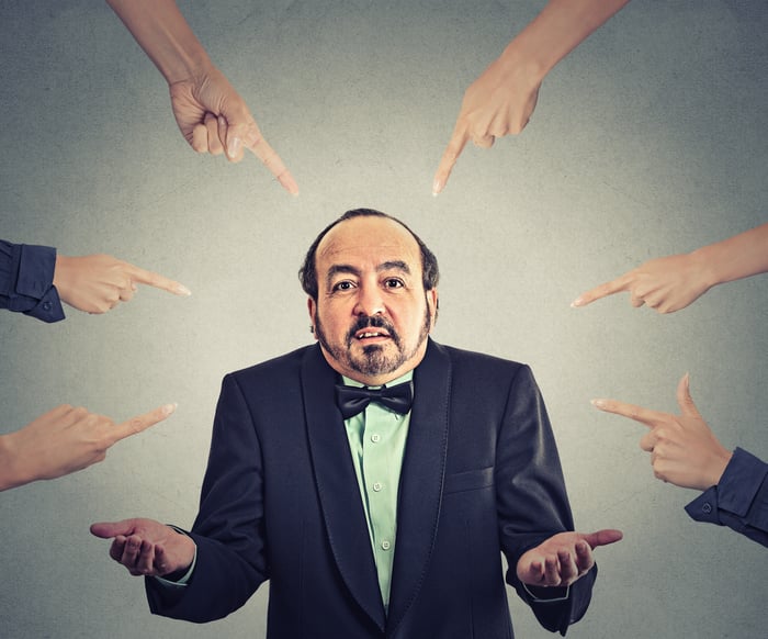 man in suit being pointed at by many fingers