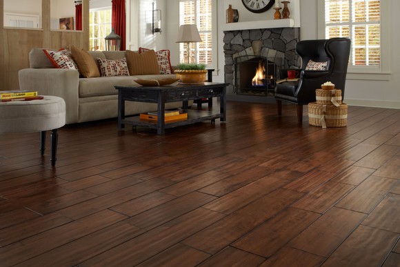 Room with wood flooring prominently featured among furniture and fireplace.