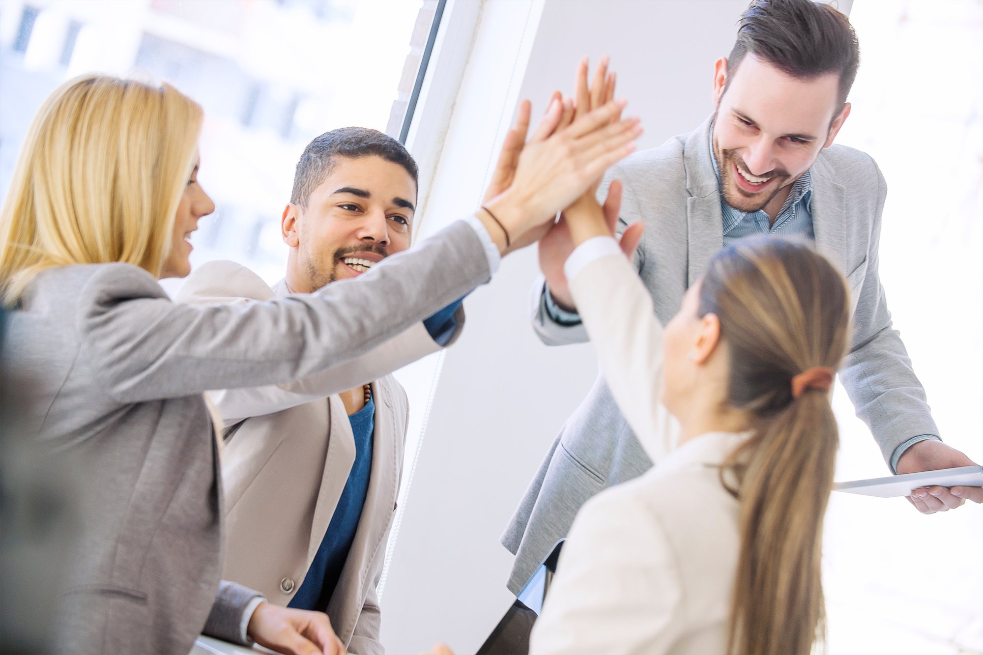Four coworkers high-fiving one another
