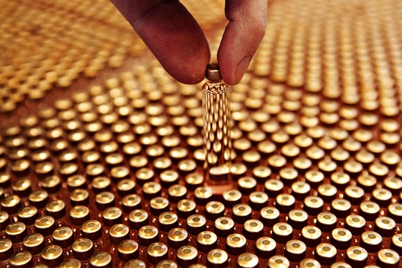 A vial of insulin held by two fingers above a tray of them