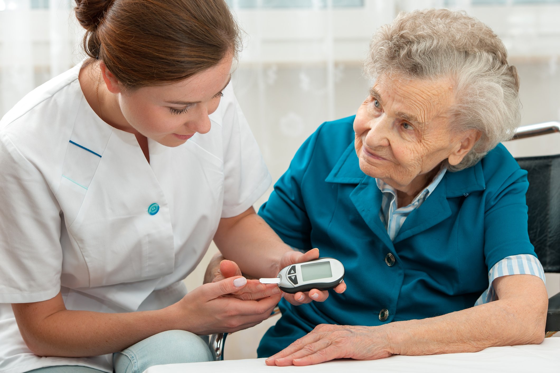 A nurse checks an elderly woman's blood sugar levels using a glucometer.