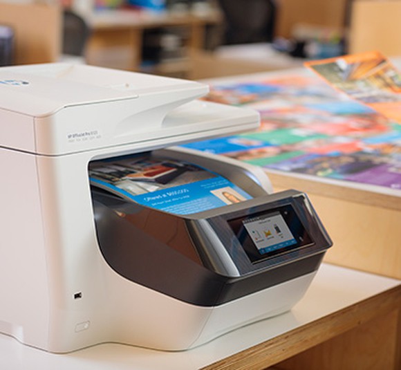 An HP inkjet printer sitting on a table in an office.