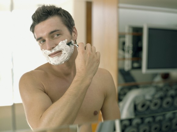 A man shaving in front of a mirror.
