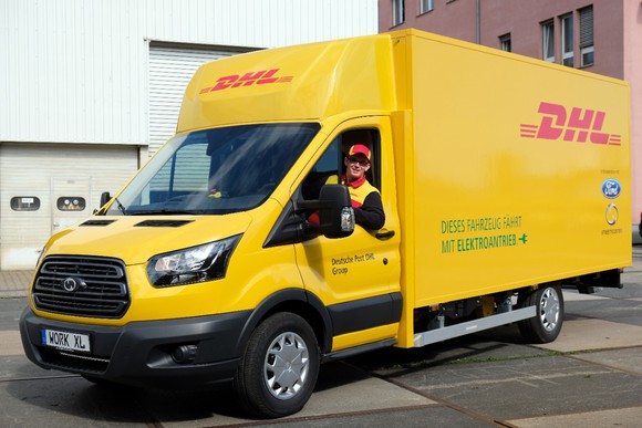 A Ford-badged electric delivery truck in yellow and red DHL livery.