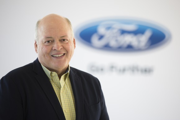 Jim Hackett is shown before a backdrop with a blurred Ford logo.