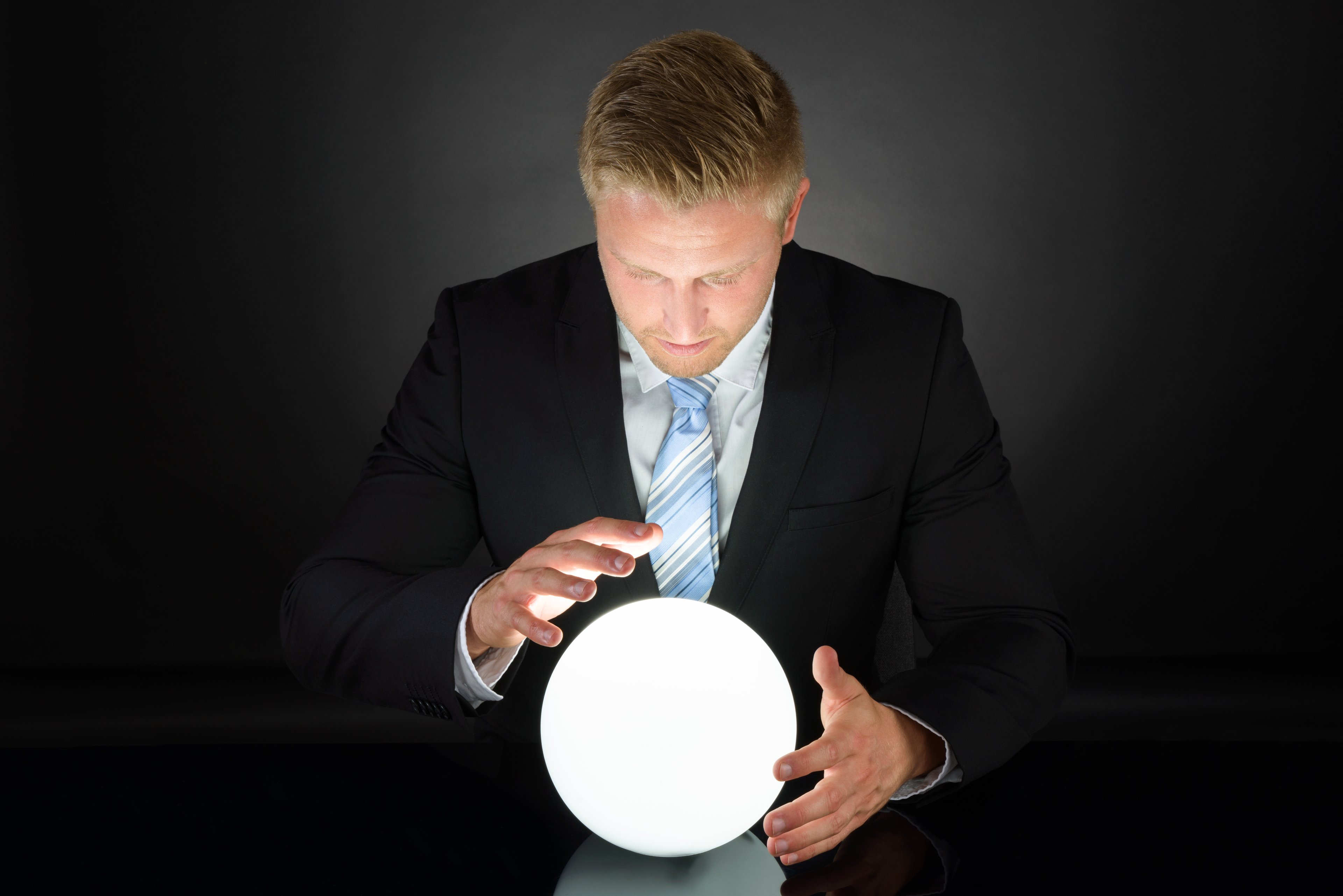 A man in a suit looking at a crystal ball.