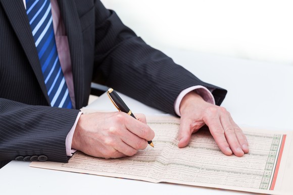 A man circling stocks in a newspaper list. 