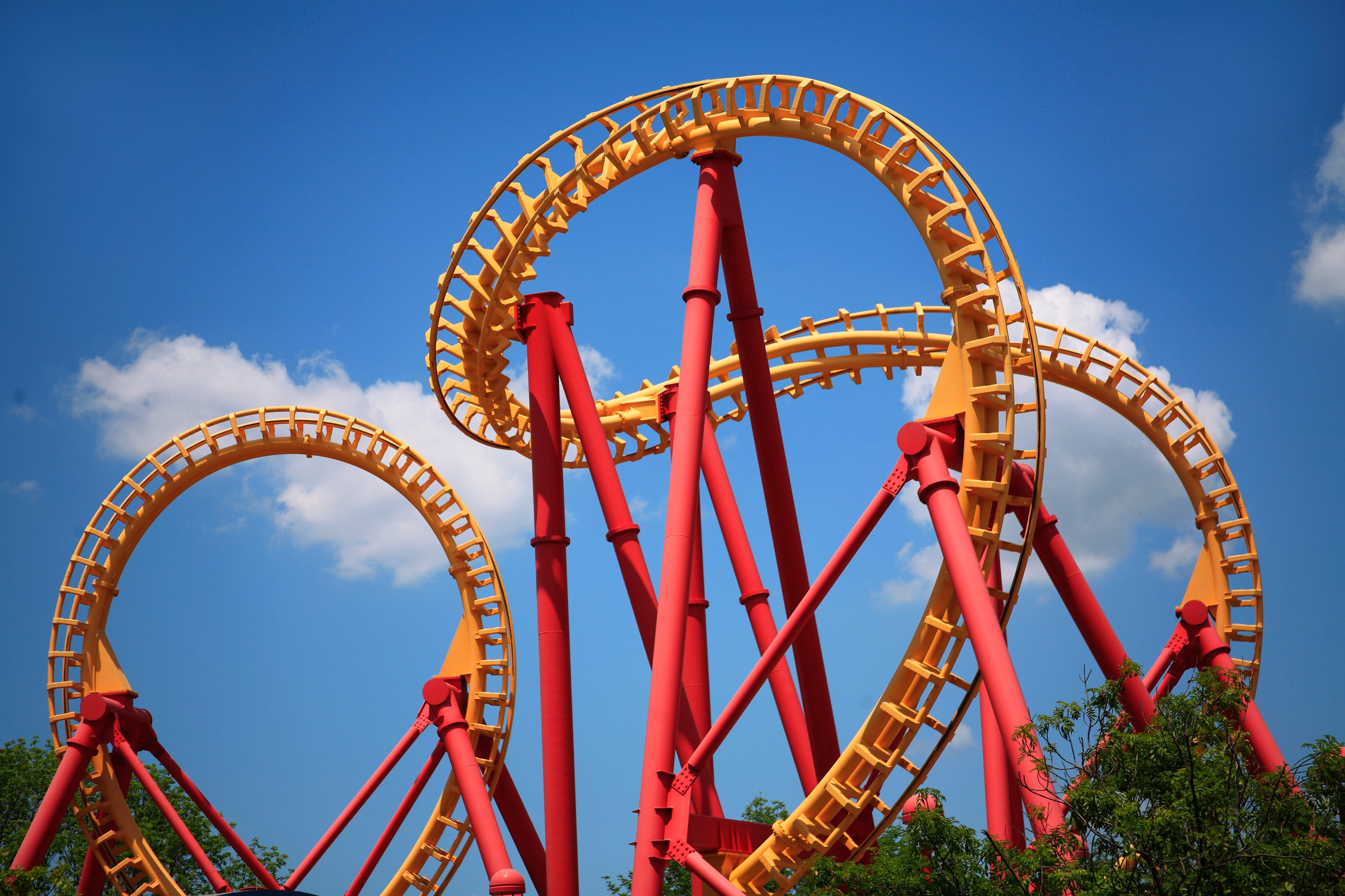 A yellow roller coaster track spirals against a blue sky.