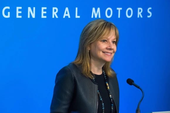 GM CEO Mary Barra smiling against a blue background, with the words "General Motors" on it