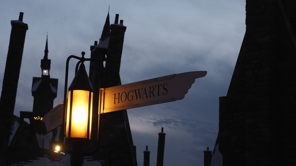an image of Hogward wizard academy at night, with a street sign lit, pointing to the right and with "Hogwarts" printed on it