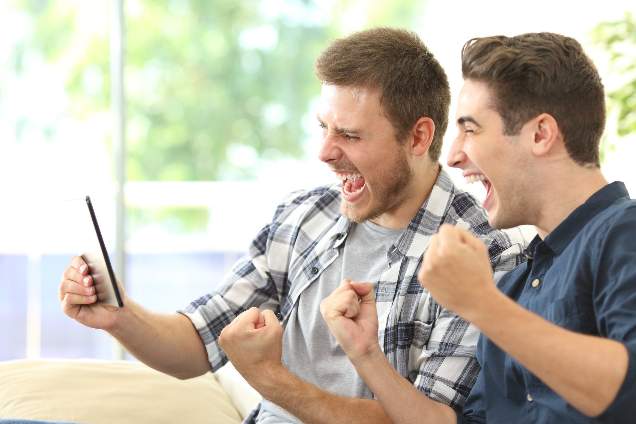 Two men excitedly streaming TV on a tablet