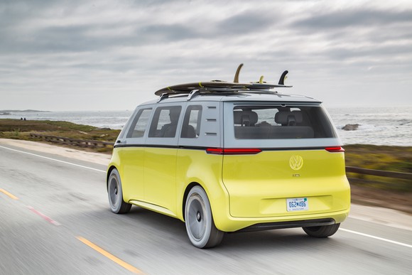 The yellow and white I.D. Buzz Concept, photographed from behind while driving on a coastal road.
