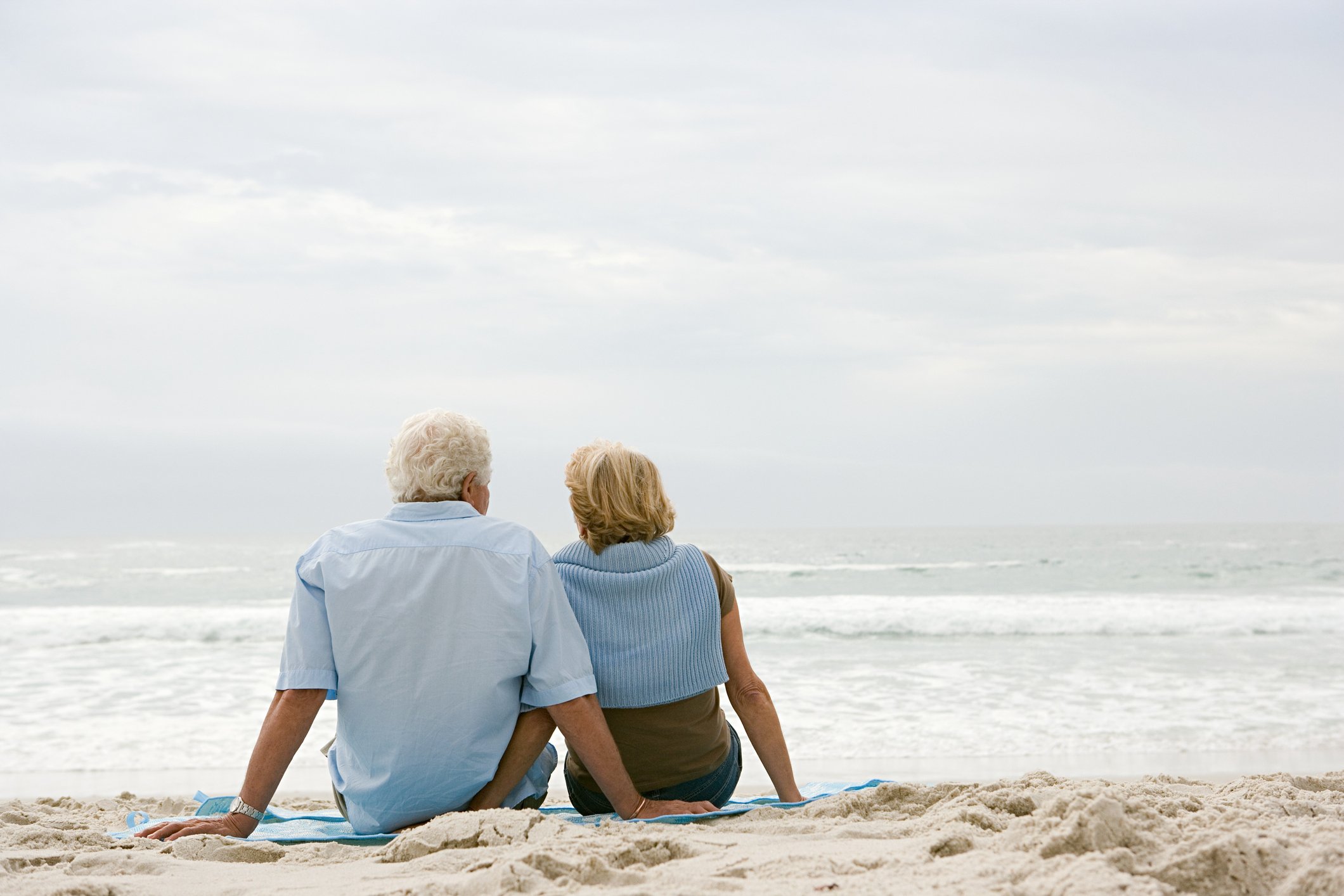 A senior couple sitting on a beach.