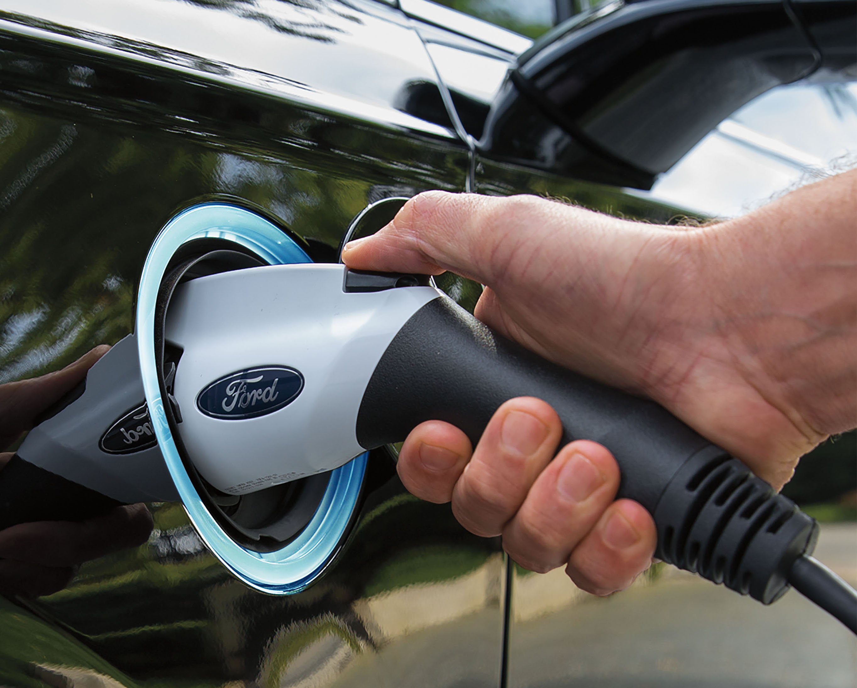 A close-up of a Ford-branded electric-vehicle charger plugged into a 2017 Ford Fusion Energi plug-in hybrid sedan.