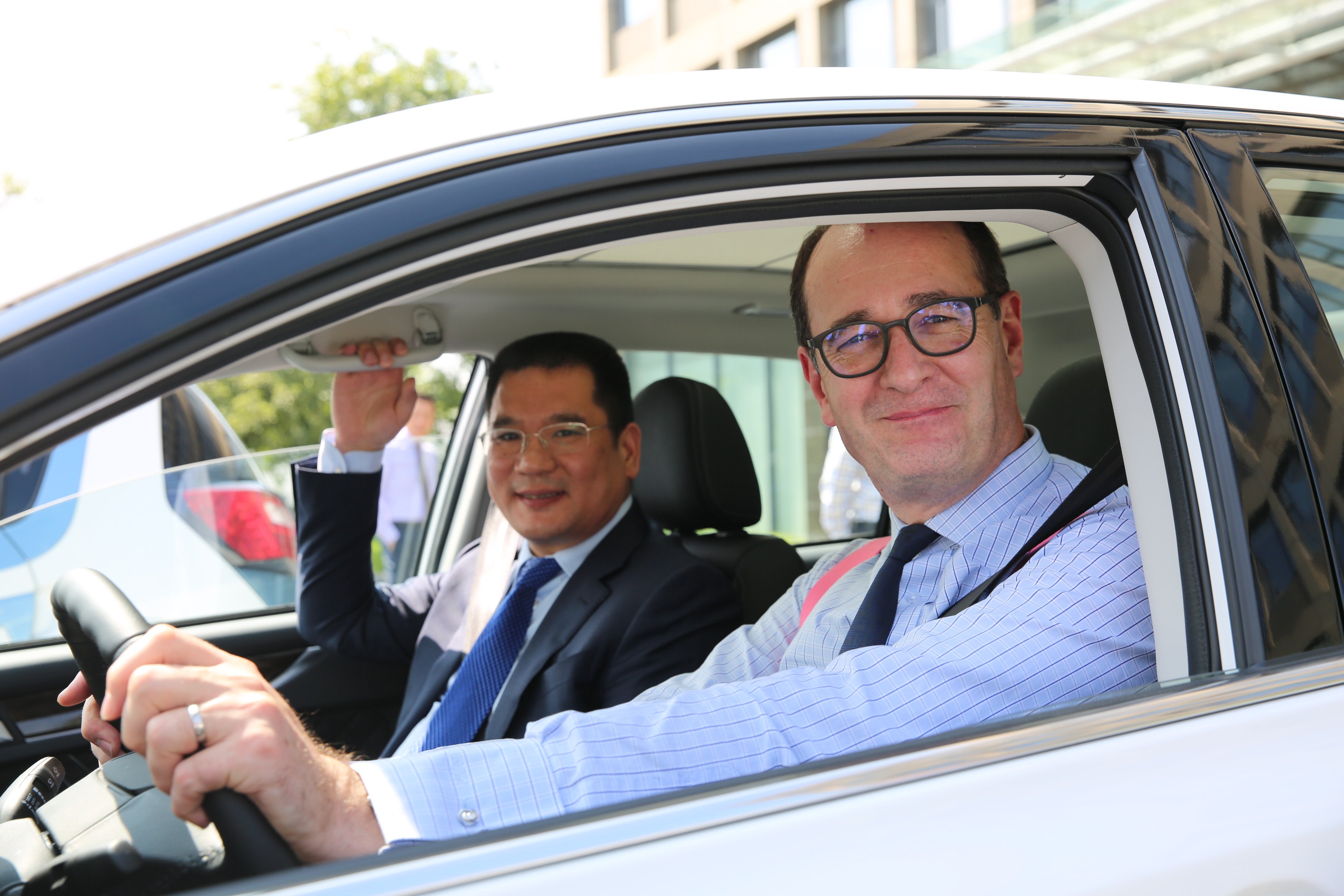 Jin Zheyong and Peter Fleet are shown inside a white car. 