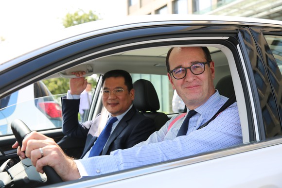 Jin Zheyong and Peter Fleet are shown inside a white car. 