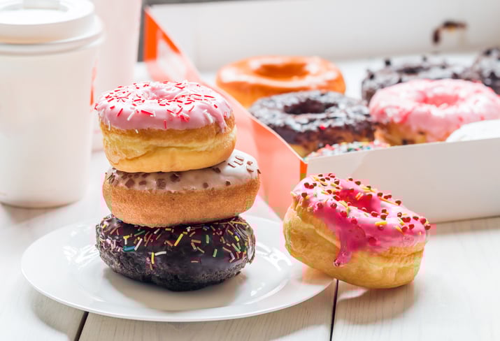 Colorful display of doughnuts, doughnuts box, and coffee resembling Dunkin' Donuts food and packaging.