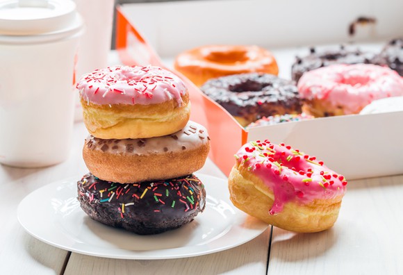 Colorful display of doughnuts, doughnuts box, and coffee resembling Dunkin' Donuts food and packaging.