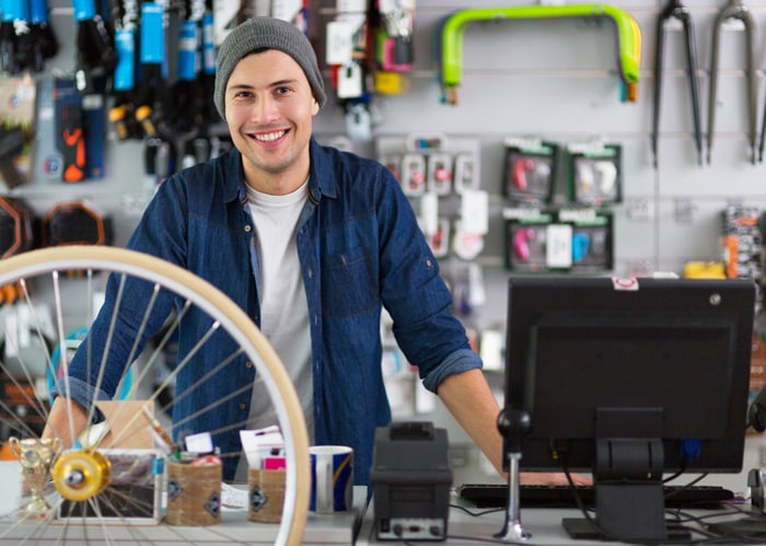Smiling man standing behind the counter in a bicycle shop. 