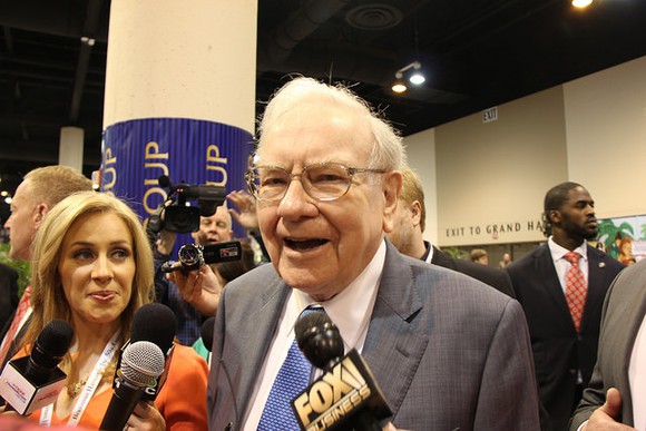 Warren Buffett speaks to someone in a convention hall.