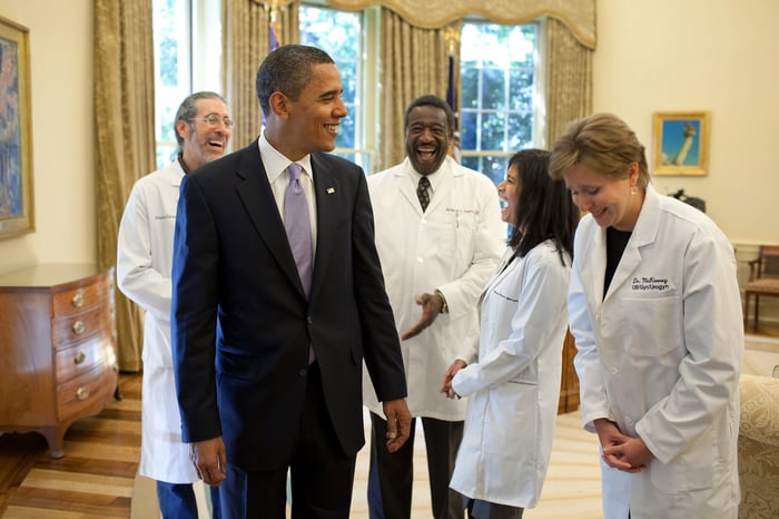 Former President Barack Obama laughing with doctors in the White House. 