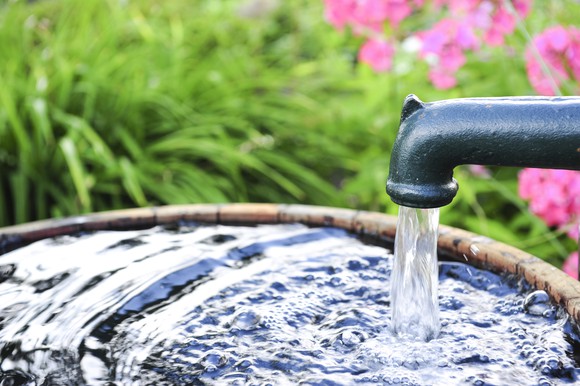 Water coming from an outdoor faucet into a bucket.
