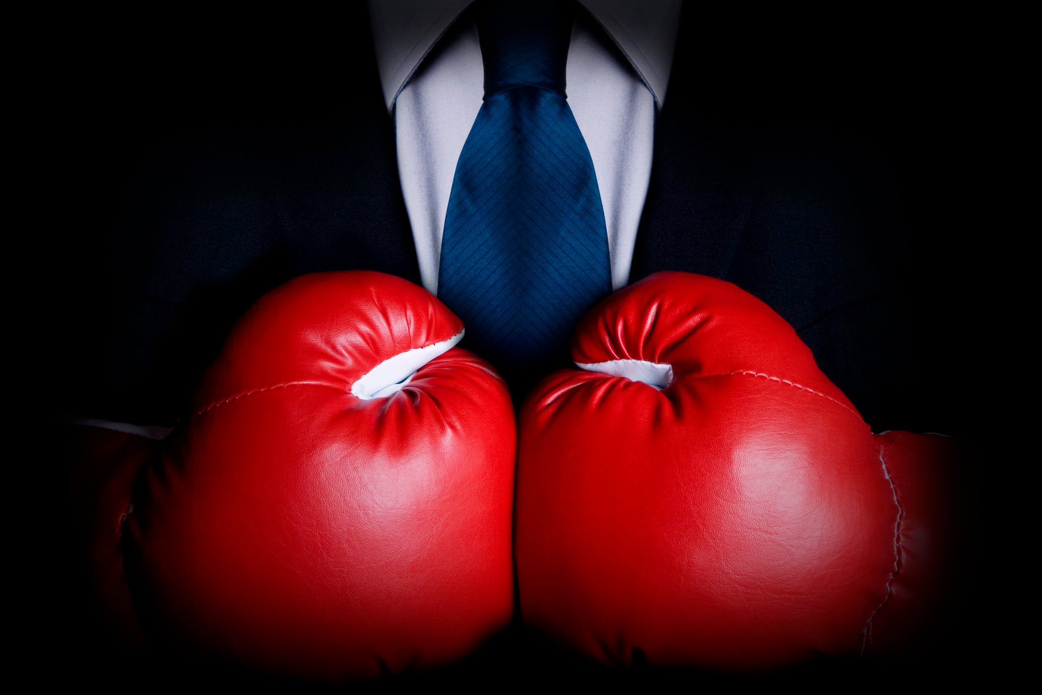 A businessman wearing big red boxing gloves.