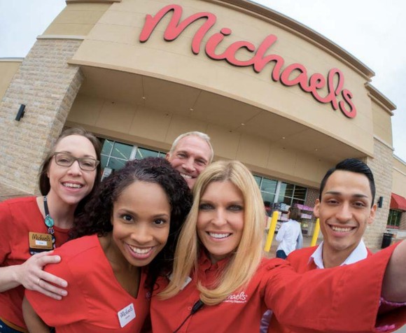 Five smiling Michaels employees taking a selfie under their store's company logo.