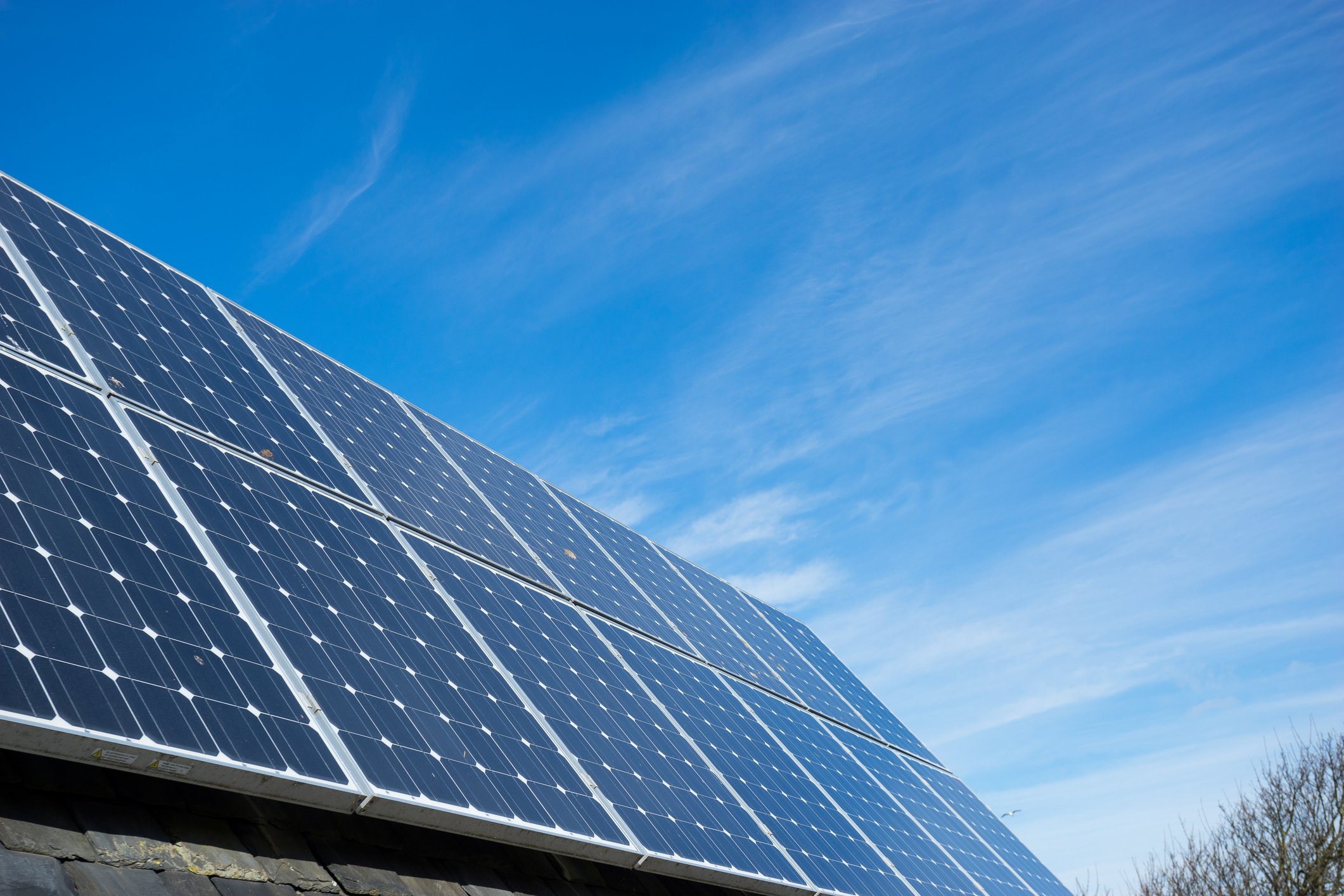 Solar panels on a residential roof with a blue sky in the background.