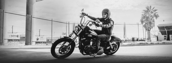 black-and-white photo of man riding a Harley-Davidson Dyna motorcycle