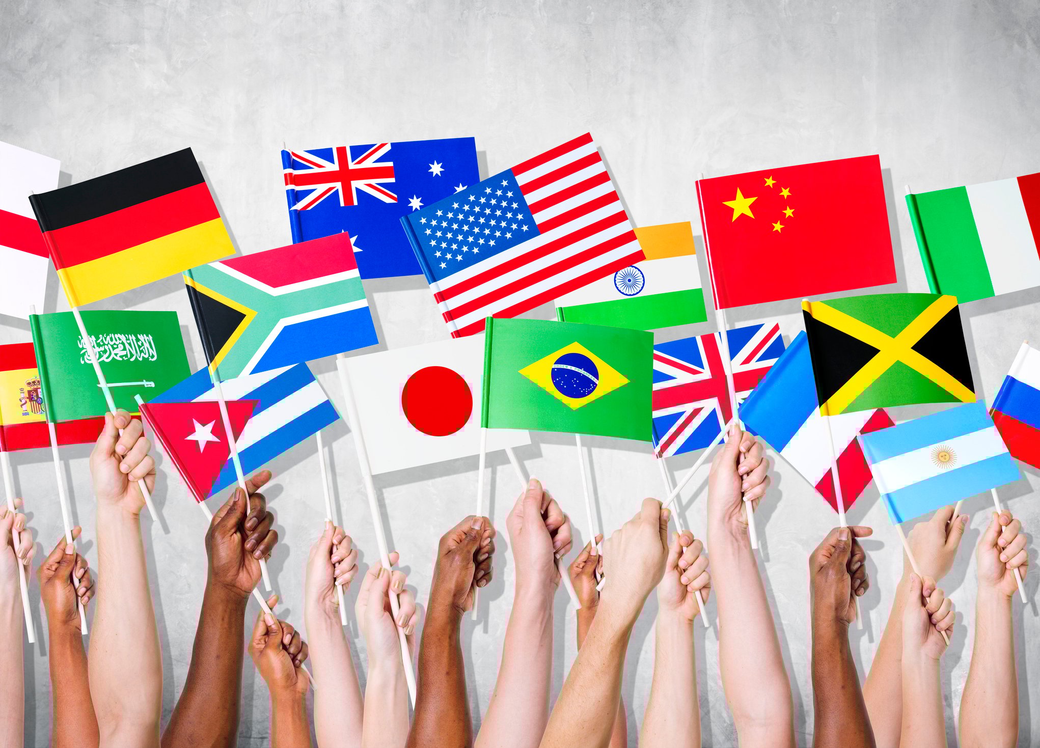 Hands holding flags of different countries.