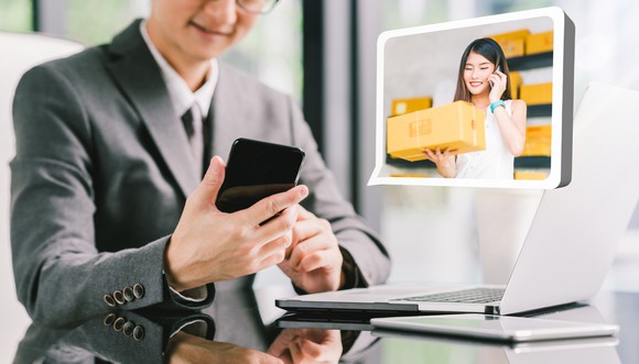 A businessman orders products from a small business owner via a smartphone app.