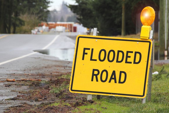 Yellow "Flooded Road" sign along side of road.
