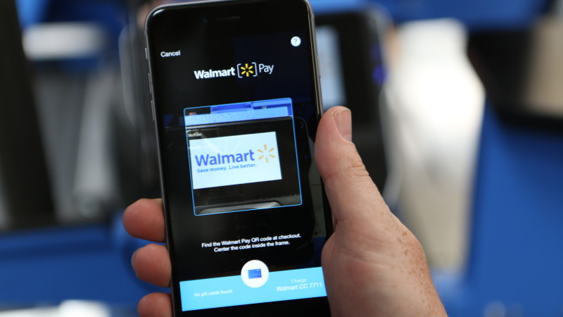 A hand holding a smartphone displaying the Walmart Pay app.
