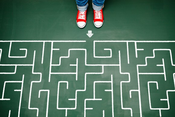 Someone with bright red shoes standing at the beginning of a complex maze.