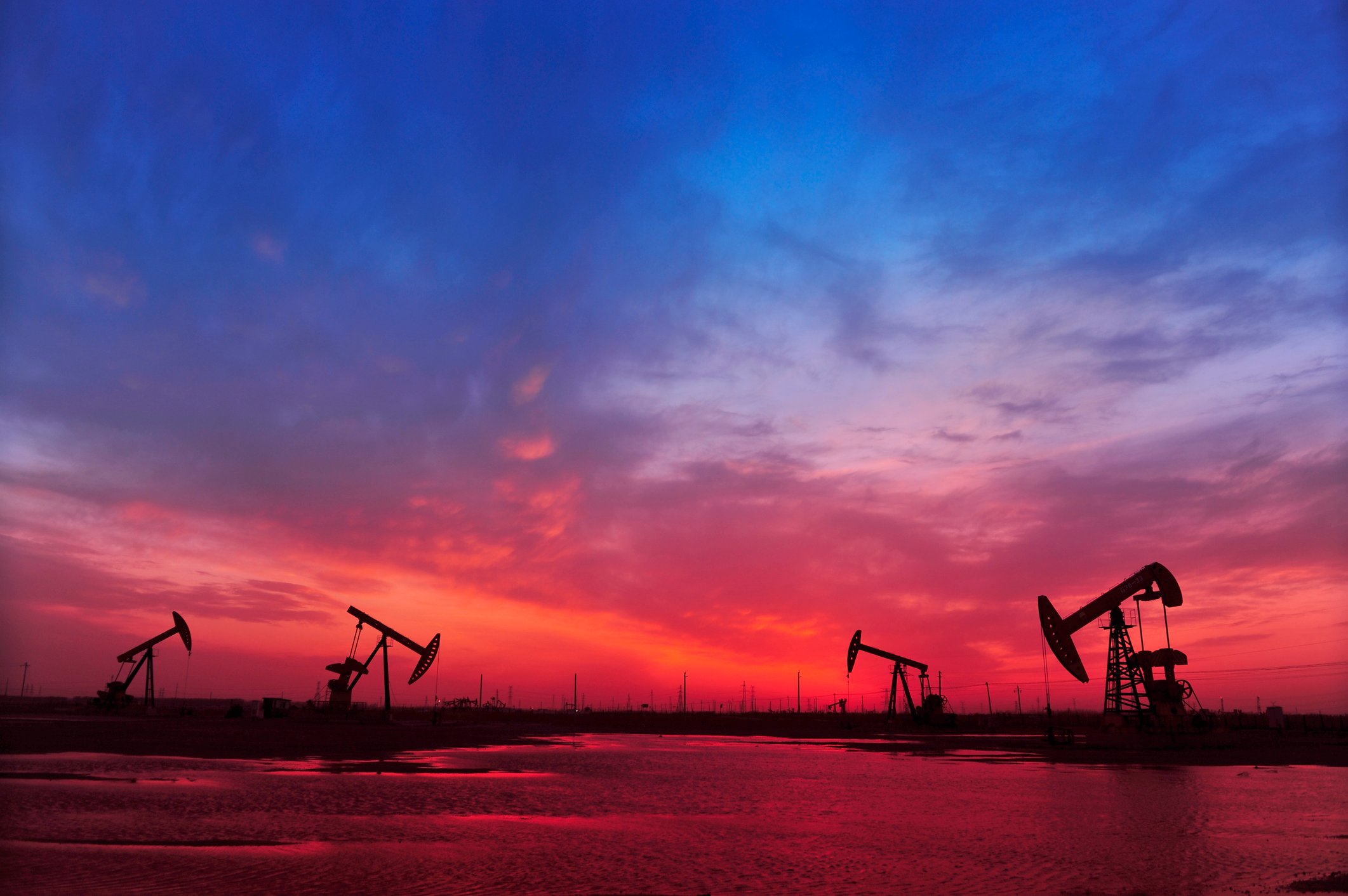Oil pumps in silhouette against colorful sky at sunset