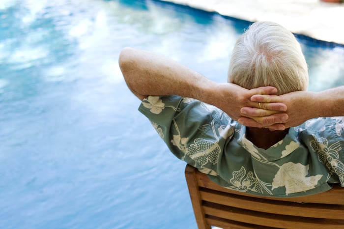 An older man reclines by a pool.