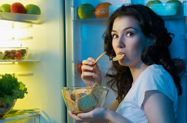Woman sneaking a snack out of the fridge