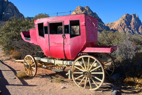 A broken-down stagecoach parked in the desert.