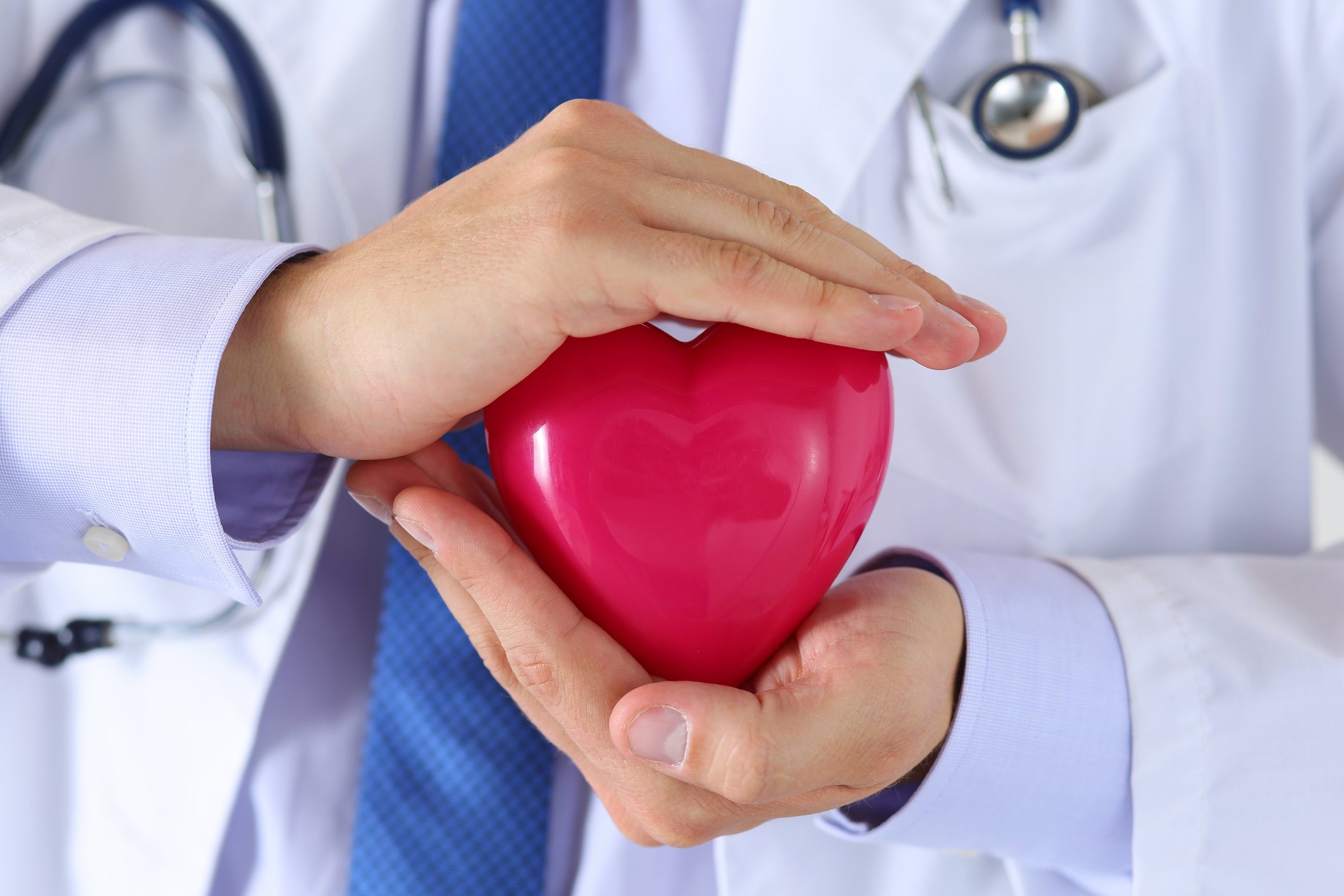 A doctor holding a red toy heart between his hands