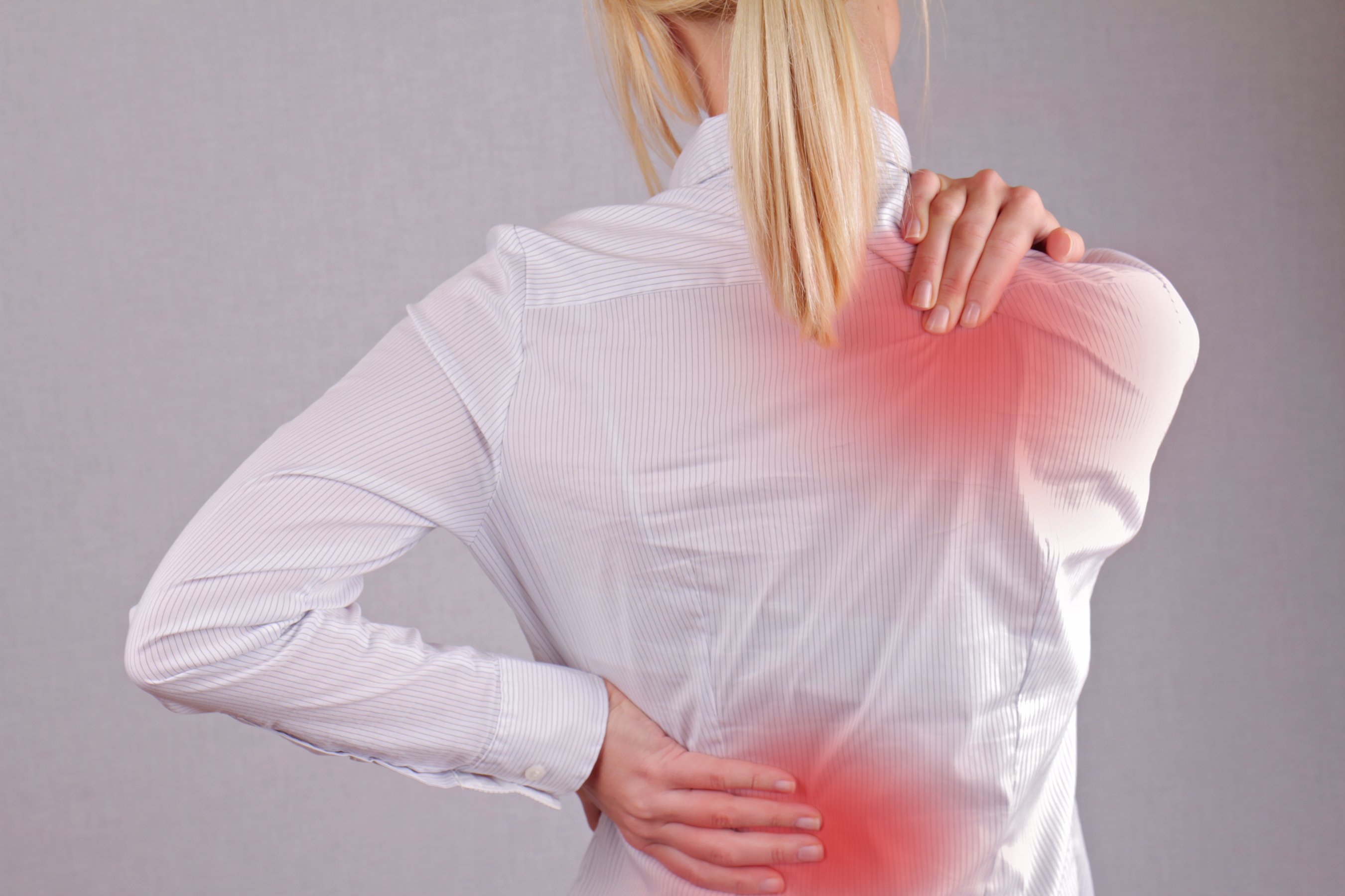 A woman rubbing her upper and lower back in pain