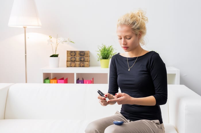 A woman sitting on a couch with a diabetes lancet