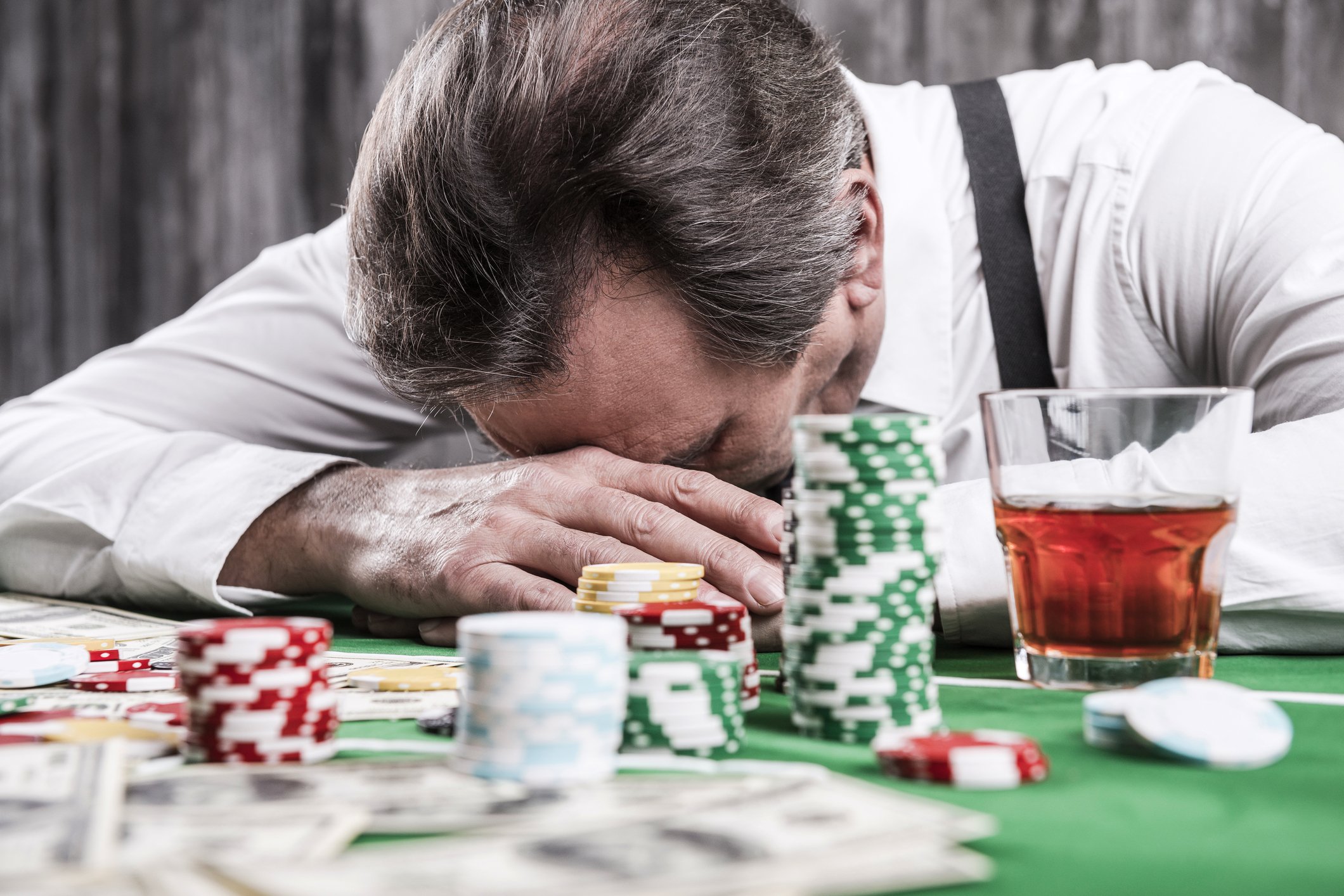 A man with his head down on a poker table