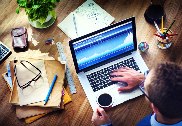 Man looking at a stock chart on his laptop while drinking coffee