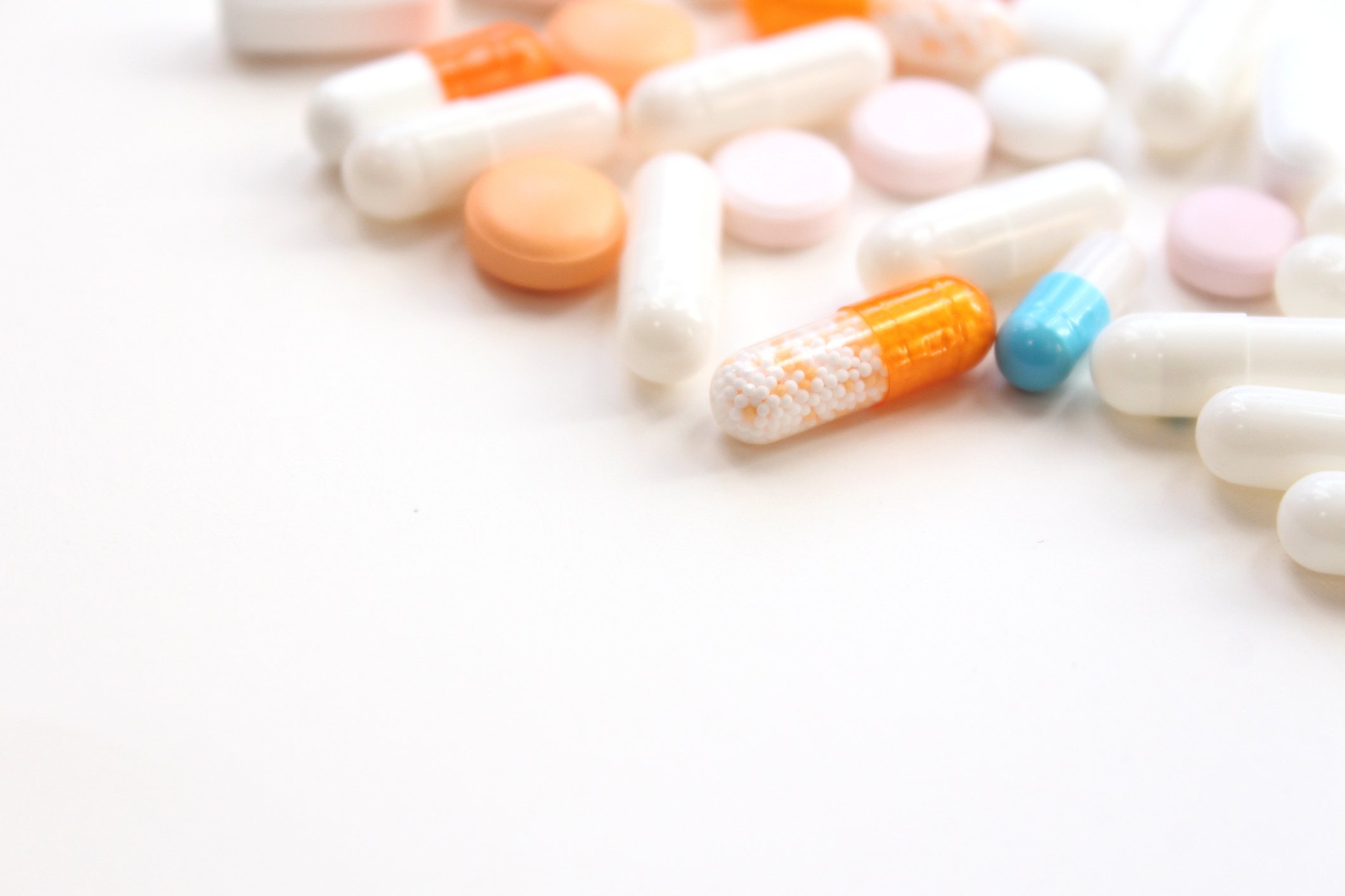 Assortment of pills laying on a white table. 