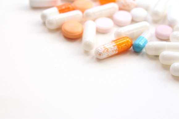 Assortment of pills laying on a white table. 